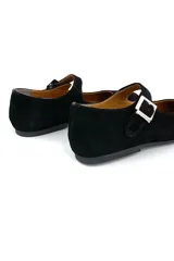 Zapato tipo Mary Jane de gamuza color negro, con punta redondeada y tira sobre el empeine con hebilla plateada.