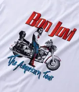 Remera de algodón color blanco con estampado frontal de la banda Bon Jovi y la leyenda The American Tour. Presenta cuello redondo y mangas cortas con un corte regular.