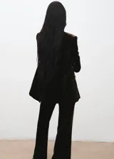 Blazer de terciopelo color marrón oscuro, con cuello de solapa, cierre frontal de doble botonadura y bolsillos con solapa. Presenta un diseño recto y forro interior.