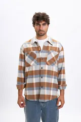 Sobrecamisa de manga larga con diseño a cuadros en tonos tostado, gris y blanco. Presenta cuello clásico, cierre frontal con botones y dos bolsillos delanteros con solapa.