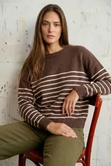 Sweater de punto con diseño a rayas horizontales negras sobre base color crema, cuello redondo, mangas largas y puños acanalados.