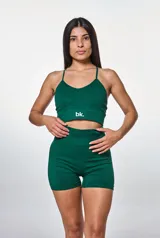 Conjunto deportivo de dos piezas color verde, compuesto por un top de breteles finos con logo estampado y un short de tiro alto ajustado.