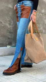 Pantalón de jean celeste con cintura elastizada, corte recto, bolsillos laterales y aplique de cuero marrón en el frente. Presenta botones metálicos en los laterales y etiqueta de cuero en la parte posterior.