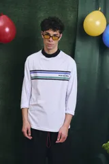 Remera de manga larga blanca con cuello alto en color azul. Presenta franjas horizontales de colores en el pecho y el logo de la marca estampado.
