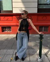 Top negro translúcido y brillante, de corte halter y diseño asimétrico con terminación más larga en la parte trasera.