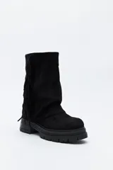 Bota de caña media con flecos laterales, confeccionada en material con textura tipo gamuza. Presenta una silueta relajada y suela robusta con base dentada.