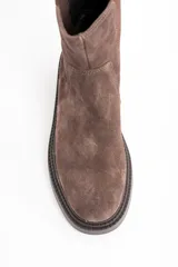 Bota tipo Chelsea de caña media, confeccionada en gamuza color marrón. Presenta paneles laterales elásticos al tono y una suela de goma robusta con plataforma baja y taco cuadrado.