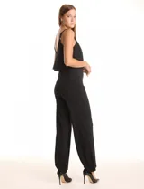 Enterito negro de crepe con escote en V, breteles finos ajustables y una capa suelta en la parte superior. La cintura es definida con corte anatómico y el pantalón tiene pierna ancha de caída fluida. Cierre invisible en la espalda.