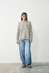 Sweater de punto con diseño jaspeado en tonos grises, cuello alto y corte holgado con mangas largas.