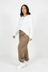 Babucha estilo cargo color beige, con corte holgado, cintura elástica con cordón ajustable, bolsillos laterales funcionales y puños elásticos en los tobillos.