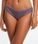 Bombacha de bikini tipo bikini, confeccionada en encaje rústico con estampado floral. Color lila/malva, con borde de encaje festoneado y un pequeño lazo decorativo con dije en el centro frontal.