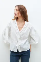 Blusa blanca de manga larga con escote en V y bordados en el frente.
