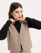 Chaleco de vestir gris oscuro con textura tipo tweed, escote en V y botones frontales. Corte levemente entallado y largo a la cintura.