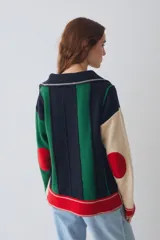 Buzo estilo polo de lambswool con diseño color block a rayas verticales en tonos beige, marrón y rojo. Presenta cuello camisero, cartera frontal con botones, mangas largas con coderas y tajos laterales en el ruedo.