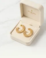 Aros tipo argolla de acero con baño de oro, con diseño texturizado de líneas verticales en relieve.