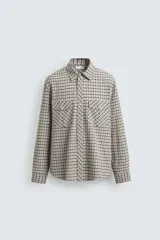 Camisa de corte relajado con estampado de cuadros, cuello solapa, manga larga con puños abotonados y bolsillos frontales de plastrón con solapa. Cierre frontal con botones a presión.