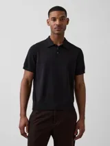 Buzo tipo polo de manga corta en tejido de punto color negro, con cuello y cierre frontal parcial con botones.