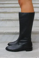 Bota de caña alta confeccionada en cuero vacuno negro, con diseño de cuero calado en la caña y puntera redondeada.