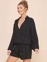 Blusa Allie Rose de color negro, corte holgado con escote en V cruzado y cuello camisero. Presenta mangas largas amplias con puños sutilmente fruncidos y diseño de silueta fluida.