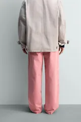 Pantalón relaxed fit color rosado, confeccionado en tejido de algodón con efecto lavado. Presenta pliegues frontales, bolsillos delanteros y bolsillos traseros de vivo. Cierre frontal con cremallera y botón.