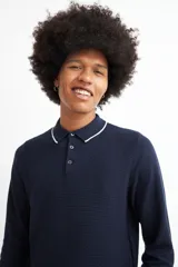 Sweater de punto color beige con cuello polo blanco y mangas largas.