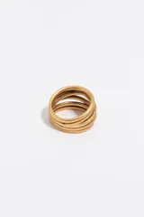 Anillo ancho de metal dorado con diseño multicapa de aros entrelazados y acabado mate.