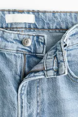 Pantalón jean de tiro alto y corte bootcut, confeccionado en denim de algodón con ligera elasticidad. Presenta diseño clásico de cinco bolsillos, cierre frontal con botón y cremallera, y perneras ligeramente acampanadas en el bajo.