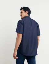 Camisa azul oscuro con pequeños lunares blancos, de manga corta y corte clásico.