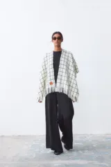 Ruana de tejido de punto con diseño a cuadros en color blanco y negro, con terminación de flecos en el ruedo.