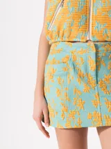 Minifalda celeste con estampado de flores amarillas, tiro bajo, bolsillos frontales y cierre con cremallera.