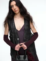 Chaleco sastrero de denim negro con diseño de cuadros y aplicación de lentejuelas sutiles. Presenta escote en V, cierre frontal con botones metálicos y bolsillos delanteros.
