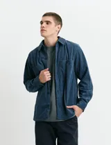 Sobrecamisa de pana color marrón, con manga larga, cierre frontal con botones y dos bolsillos frontales con solapa y botón.