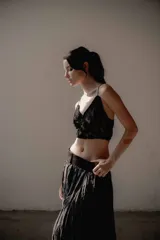 Top corto de encaje negro con breteles finos y detalle de plumas desmontables en el escote. Presenta un diseño ajustado al cuerpo con forro interior.