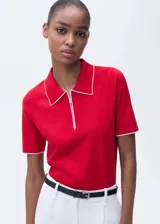 Jersey de punto fino color rojo con cuello polo y cierre frontal. Presenta ribetes en contraste color blanco en el cuello y en los bordes de las mangas cortas.