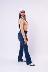 Jean de corte oxford con tiro alto, confeccionado en denim azul oscuro. Presenta un diseño ajustado en la parte superior que se ensancha gradualmente desde la rodilla hacia el ruedo.