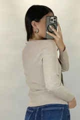 Buzo de hilo gris con textura acanalada, escote en V y cierre frontal con botones pequeños.