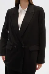 Blazer blanco de corte holgado, con cuello solapa, doble botonadura y bolsillos delanteros.