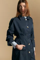 Trench azul marino de corte clásico con cuello amplio, botones frontales grandes en color beige, y detalles en los hombros.