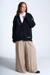 Cárdigan color beige con botones negros, escote en V y detalles de costuras bordadas en negro.