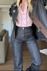 Pantalón negro de tela impermeable engomada con tajo en el tobillo y pespuntes color óxido.