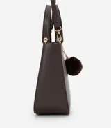 Cartera satchel mediana color beige, con cierre de cremallera, correa de mano y bretel largo desmontable. Incluye un llavero de pompón de piel sintética.