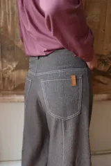 Pantalón de corte wide leg en color marrón, con tiro medio, cierre frontal con botón metálico y costuras visibles a contratono.