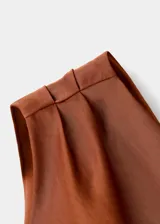 Vestido midi de satén color cobre con diseño asimétrico de un solo hombro. Presenta un detalle fruncido lateral que recorre el costado, cierre de cremallera lateral y una abertura en el bajo.