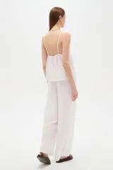 Musculosa blanca de algodón con diseño de broderie, escote en V, tirantes finos regulables y corte holgado.
