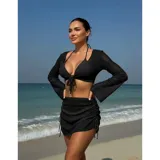 Conjunto de baño de cuatro piezas en color negro, confeccionado en tejido de malla transparente. Incluye un top de bikini triangular, una remera manga larga abierta con lazo frontal para anudar, y una pollera corta ajustable con cordones laterales.