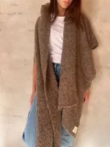 Chal de punto bouclé color marrón claro, hecho de 100% baby alpaca. Tejido suave, esponjoso y cálido, ofrece una textura envolvente y lujosa.