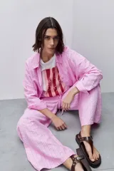Pantalón de tiro alto color rosado con textura a rayas, corte amplio y silueta fluida, con cintura elástica y lazo de ajuste.