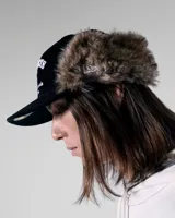Gorra de pana negra con orejeras forradas en piel sintética y visera plana. Presenta un bordado frontal con el nombre de la marca Twojeys, estrellas y texto decorativo en color blanco.