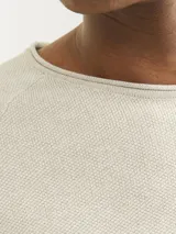 Sweater de manga larga con cuello redondo, confeccionado en tejido de punto con textura estructurada. Presenta un diseño minimalista con un pequeño parche de marca en el ruedo inferior.