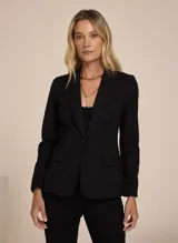 Blazer negro entallado de tela lisa, con solapas de pico, bolsillo frontal incorporado y solapas aplicadas, mangas largas, cierre de botones en la parte delantera y forro incorporado.